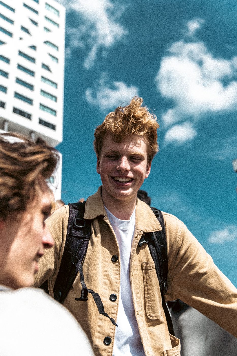 Lachende man met rugzak voor een blauwe lucht